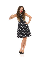 Beautiful Young Woman In Black Cocktail Dress In Polka Dots And High Heels Is Showing Thumb Up.