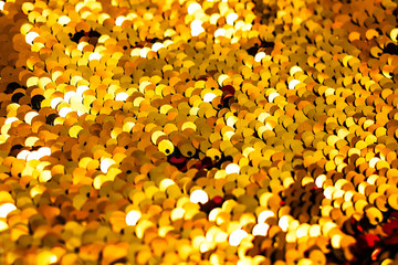 Background of golden sequin. Fashion shiny fabric. Scales of round sequins. Festive abstract glittery background.