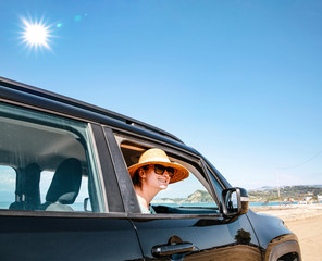 Naklejka premium A woman in a black car on a sandy beach and blue ocean view.
