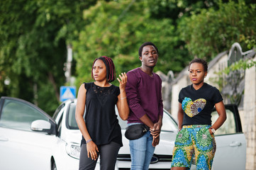 Three african american friends stay near car.