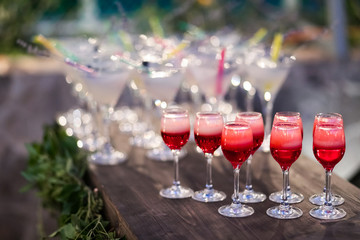 Set of red cocktails on the bar counter. Night club, evening party. Lights bokeh on background