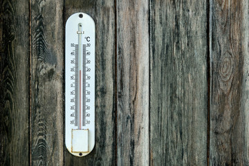 Old outdoor thermometer on the wooden wall with a copy space