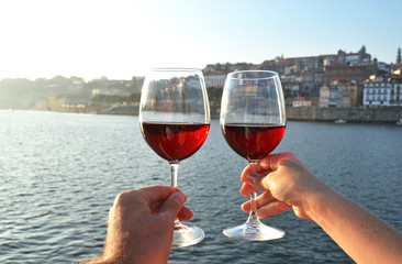 Wine glasses in the hands against Douro river in Porto, Portugal