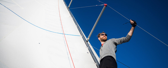 Low angle view of sailor operating windlass on yacht. Working with ropes and sail