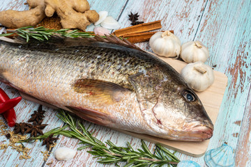 Fresh Golden Snapper on wooden table, Surrounded by spices and raw ingredients