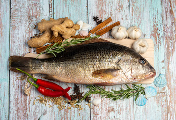 Fresh Golden Snapper on wooden table, Surrounded by spices and raw ingredients