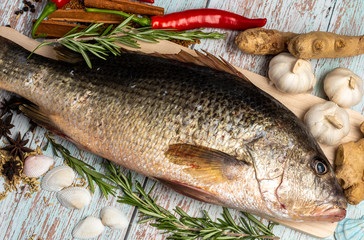 Fresh Golden Snapper on wooden table, Surrounded by spices and raw ingredients