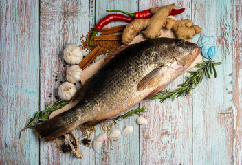 Fresh Golden Snapper on wooden table, Surrounded by spices and raw ingredients