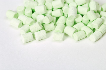 Fototapeta na wymiar Gentle green marshmallows on white paper background with copy space. Sweet food. Selective focus. Pastel color.