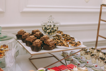 Beautifully decorated catering banquet table with burgers, profiteroles, salads and cold snacks. Variety of tasty delicious snacks on the table