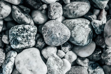Gray pebbles background, macro. Grey rubble stones on the sea shore abstract backdrop.