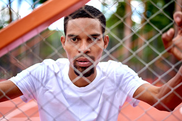 Black basketball player holding the chain link fence with hands