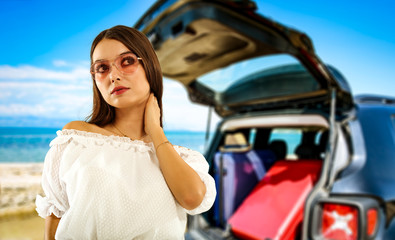 Summer background with a girl and black car in a beautiful sunny sandy beach and blue ocean view.