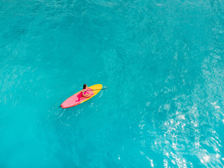 Aerial view of woman on stand up paddle board in blue ocean.