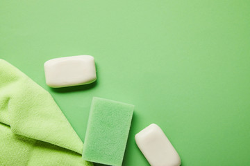 top view of white soaps, rag and sponge on green background