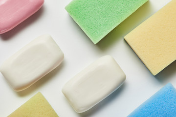 top view of white and pink soaps, colorful and bright sponges