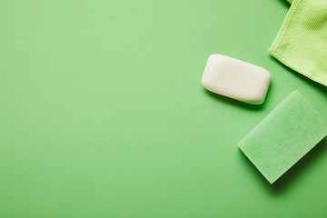top view of white soap, rag and sponge on green background
