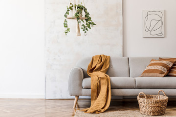 The stylish boho compostion at living room interior with design gray sofa, rattan basket, mock up...