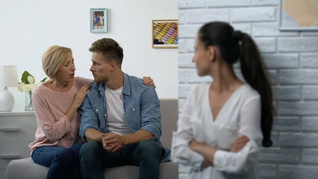 Offended woman secretly watching mother-in-law consoling husband after quarrel