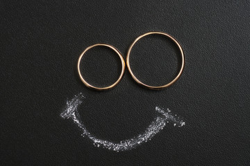 Wedding rings and smile drawing with calk on calkboard.