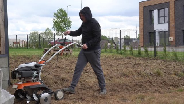 Weak man start engine of cultivator and work hardly in townhouse yard