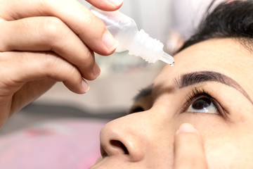 Closeup woman using eye drop. Woman applying eye drops healthcare concept.