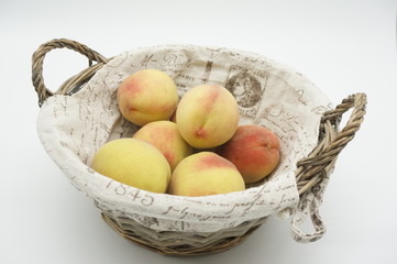 Basket with very sweet peaches on white background