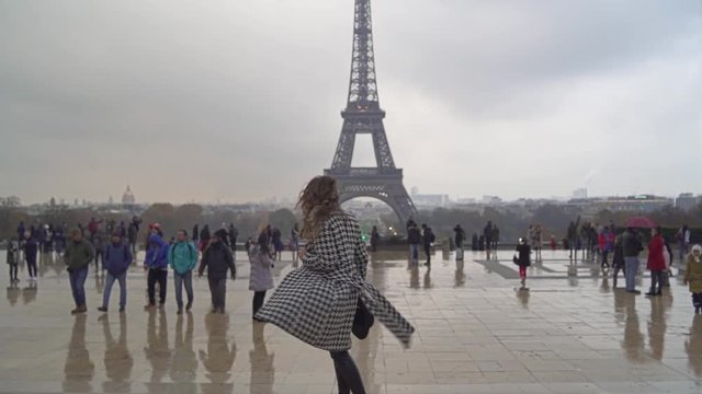 Young girl with long hair walking and smiling in a front of Eiffel Tower.