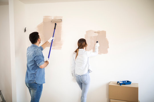 Young couple painting walls with painting tools.