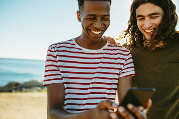 Two friends using a smart phone outdoors