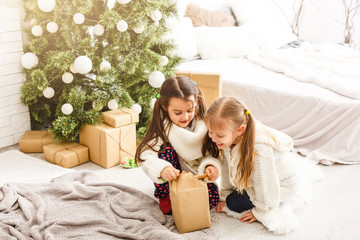 Obraz na płótnie Canvas Kids little sisters hold gifts boxes interior background. What a great surprise. Small cute girls received holiday gifts. Best toys and christmas gifts. Children friends excited unpacking their gifts.