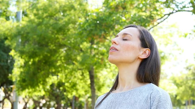 Adult woman relaxing breathing deep fresh air in a park