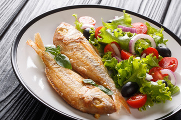 Healthy baked pink dorado served with lemon and fresh vegetables close-up on a plate on the table. horizontal