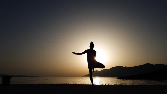 silhouette of woman staying in yoga pose at sunset on beach with free space