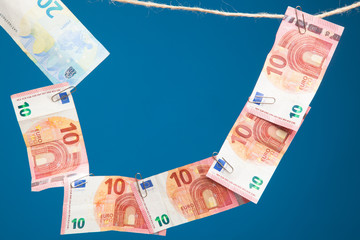 Billetes de dinero colgados de una cuerda por clips metálicos sobre fondo azul oscuro. Billetes de...