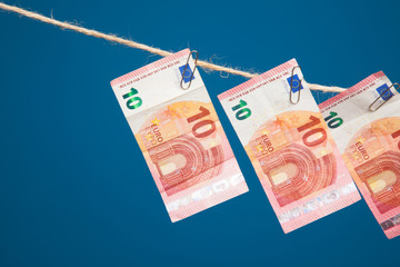 Billetes de dinero colgados de una cuerda por clips metálicos sobre fondo azul oscuro. Billetes de...