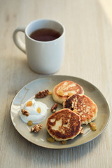 Close-up of homemade cheese pancakes syrniki with sour cream and cup of tea