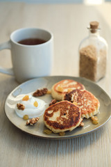 Close-up of homemade cheese pancakes syrniki with sour cream and cup of tea