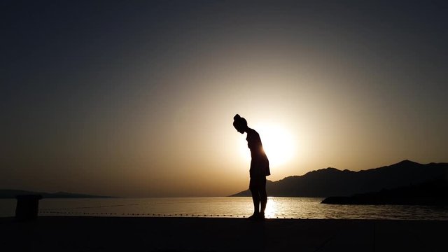 silhouette of woman practicing yoga on beach at sunset with free space