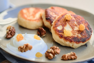 Close-up of homemade cheese pancakes syrniki with sour cream and cup of tea