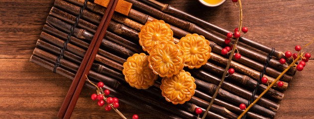 Moon cake Mooncake table setting - Chinese traditional pastry with tea cups on wooden background, Mid-Autumn Festival concept, top view, flat lay.