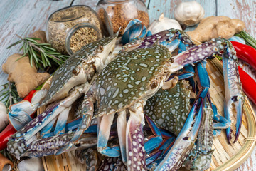 Fresh Raw Crab surrounded by spices and ingredients on a wooden table