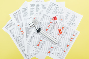 Fototapeta premium widok z góry probówki z napisem testu alergii i dermatoskopem na wynikach testu alergii na żółtym tle