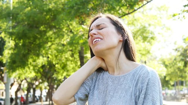 Adult woman complaining suffering neck ache in a park