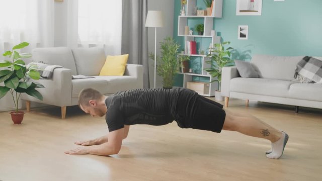 Young man does push-ups in the afternoon in his living room