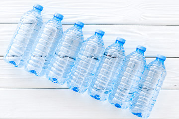 Plastic bottles with pure water on white wooden background top view