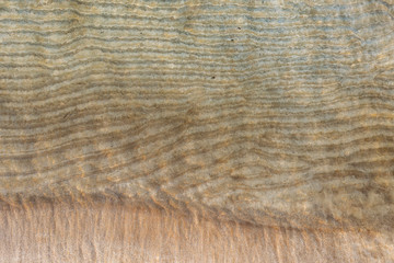 Sandy beach coastline with crystal sea water and small waves background.