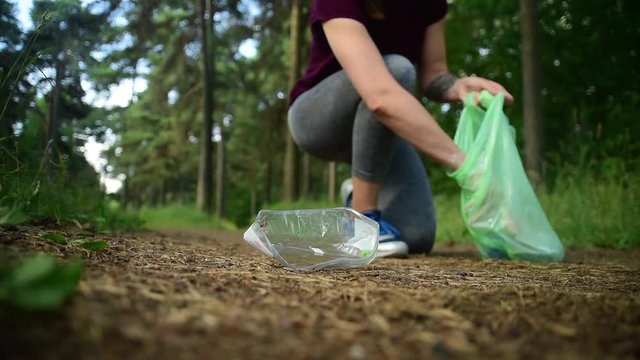 Woman jogging with garbage bag in forest. Collecting trash. Plogging concept