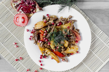 baked veal with tomatoes decorated with herbs and fruits pomegranate Caucasian cuisine