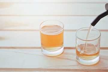 closeup pour a small glass of liquor on wood table.